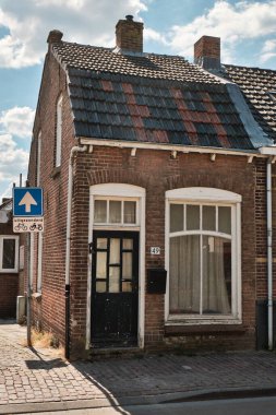 12 Mayıs 2025 - Ovezande-Hollanda: Hollanda 'nın Zeeland ilinin kırsal kesimindeki Ovezande köyünde, yıpranmış kapısı ve fayanslı çatısı olan dar tuğlalı ev.