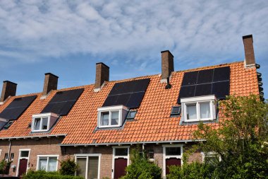 31 Mayıs 2025 - Middelburg-Hollanda: Tipik bir 1930 Sosyal konut bloğu birden fazla ev ve büyük bacalar arasında tekrarlanan güneş panelleri ile ev halkı için daha ucuz enerji faturaları sunuyor.