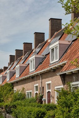 31 Mayıs 2025 - Middelburg-Hollanda: Tipik bir 1930 Sosyal konut bloğu birden fazla ev ve büyük bacalar arasında tekrarlanan güneş panelleri ile ev halkı için daha ucuz enerji faturaları sunuyor.