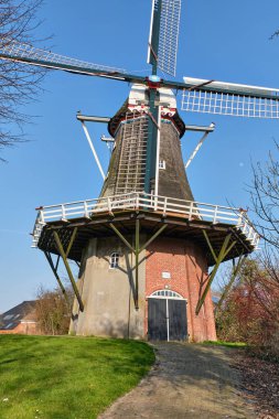 9 Mart 2025 - Pieterburen-Hollanda: 1840 Pieterburen 'de bulunan tarihi Hollanda yel değirmeni De Vier Winden, dört yelkenli ve sahneli bir kule değirmeni, açık mavi gökyüzü altında güneş ışığında duruyor.