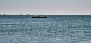 Geleneksel midye balıkçı teknesi BRU 48 Zeeland, Hollanda 'da Oosterschelde' de, sakin su ve ufukta görünen bir yelkenli yatı ile berrak mavi gökyüzünün altında..