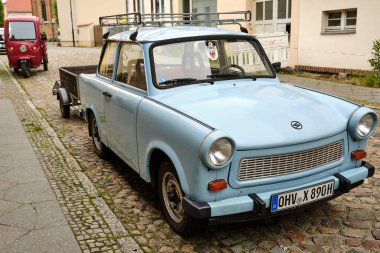10 Haziran 2025 - Fuerstenberg-Almanya: Berlin 'in kuzeyindeki tarihi Doğu Almanya kasabası Fuerstenberg' in kaldırım taşı caddesinde park etmiş açık mavi Trabant.