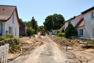 14 Haziran 2025 - Benz-Almanya: Hafta sonu tatilinde kazıcılar ve tuvaletler yol kenarında inşaat ekipmanları ve malzemelerle kazılmış bir iskan sokağına park edildi.
