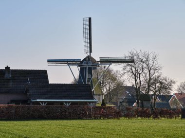 28 Mart 2025 - Miste-Hollanda: Achterhoek bölgesindeki tarihi Meenkmolen yel değirmeni, kırsal köy evleriyle çevrili, tahıl öğütmek için kullanılan tipik bir Hollanda kemer değirmeni.