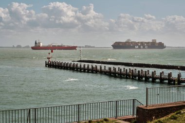 28 Mayıs 2025 - Vlissingen-Hollanda: Orta büyüklükte bir tank gemisi ve büyük bir MSC konteyner gemisi Vlissingen yakınlarındaki Westerschelde nehrinden geçiyor, Vlissingen Pilotları 'nın rıhtım ve seyrüsefer fenerlerini bulutlu bir gökyüzü altında geçiriyorlar..