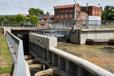 23 Haziran 2025 - Neubrandenburg-Almanya: Bir barajın yanındaki eğri beton merdiven, balıkların su seviyesi farkını aşmasına olanak sağlıyor. Şehrin nehir kıyısında modern bir altyapı.