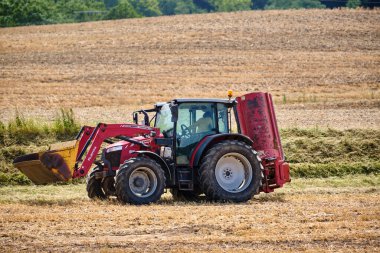 9 Temmuz 2025 - Rugen-Almanya: Modern Massey Ferguson traktörü yaz sıcağında kuru tarlaları biçerken, hasat mevsiminde kırsal çalışmaların devam ettiğini gösteriyor.