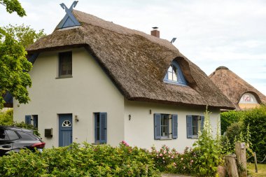 9 Temmuz 2025 - Putgarten-Almanya: Renkli cepheli geleneksel sazdan çatı evleri ve sakin bir sahil köyünde kaldırım taşı caddesi boyunca yemyeşil bahçeler.