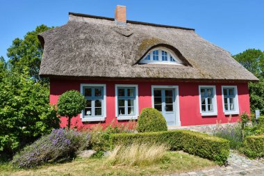 9 Temmuz 2025 - Putgarten-Almanya: Renkli cepheli ve gür bahçeli geleneksel sazdan çatı tatili.