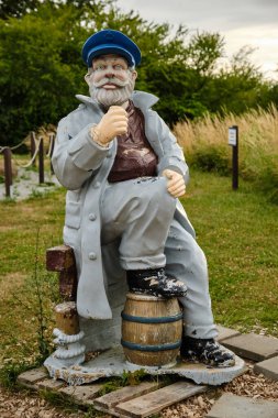 9 Temmuz 2025 - Kap Arkona-Almanya: Kap Arkona 'nın kayalıkları ve deniz mirası sahasının yakınındaki mavi başlıklı, yıpranmış yaşlı bir denizcinin gerçek büyüklükte heykeli.