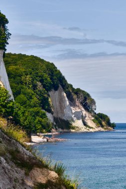 Almanya Rugen Adası 'ndaki Koenigsstuhl yakınlarında beyaz tebeşir kayalıkları. Baltık Denizi, sıcak bir yaz gökyüzü altında Jasmund Ulusal Parkı 'nda kuğularla dolu..