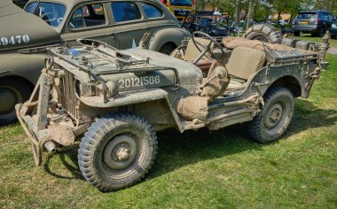 20 Nisan 2025 - Limmen-Hollanda: Kuzey Hollanda 'da tarihi bir askeri araç toplantısında çamurla kaplı 2. Dünya Savaşı' ndan kalma bir jip Amerikan Ordusu personel arabasının yanına park edildi.