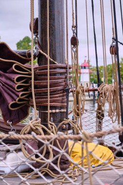 Direkli gemi direği, sarmalanmış halatlar, tahta bloklar ve Almanya 'nın Lauterbach limanına yanaşmış klasik ahşap bir yelkenliye kısmen sürgülü yelkenli..