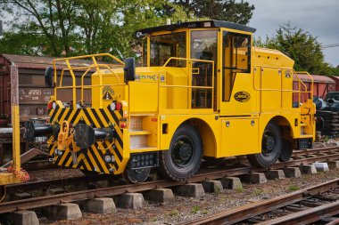 4 Mayıs 2025 - Maldegem, Belçika: Lastik lastikli ve direksiyonlu modern sarı demiryolu şalter aracı, demiryolu hattına yerleştirildi.