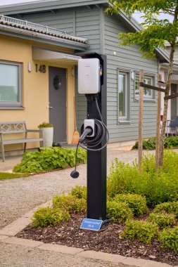 Tygelsjo, İsveç; 4 Ağustos 2025: Metal çatısı, güneş panelleri ve şarj istasyonu olan modern İsveç evleri.