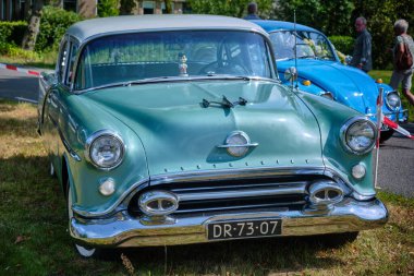 17 Ağustos 2024 - Harabe-Hollanda: Klasik nane yeşili Oldsmobile 88 'in önü krom ızgara, kaput süsü ve yuvarlak farlar yerel bir eski zaman etkinliğinde sergileniyor.