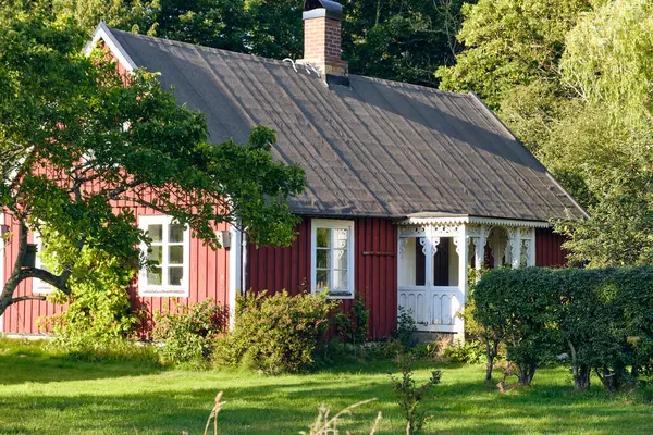 Lerhamn, İsveç; 13 Ağustos 2025: Yeşillik bahçesi ve geleneksel mimarisi olan romantik İsveç kulübesi.