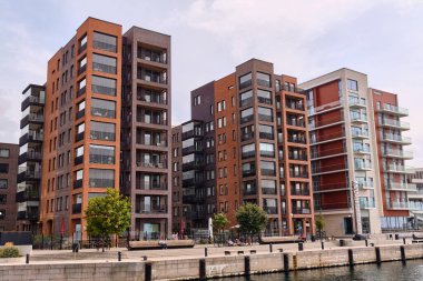Helsingborg, Sweden ; August 12, 2025: Modern urban development with brick and glass apartment buildings rising along the harbor promenade in a redeveloped waterfront district.