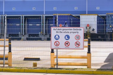 Winsen, Germany ; September 30, 2025: Three TIP rental trailers docked at Amazon distribution center behind fence with warning sign, part of e-commerce logistics and transport network.