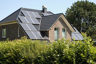 Çatıda modern siyah güneş panelleri olan tuğla ev, akıllı ev tasarımını ve Almanya 'daki yenilenebilir enerji geçişini simgeliyor..