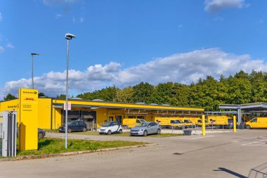 Hanstedt, Germany ; September 30, 2025: DHL Deutsche Post distribution center with yellow vans parked outside, symbolizing logistics, delivery network and local infrastructure.