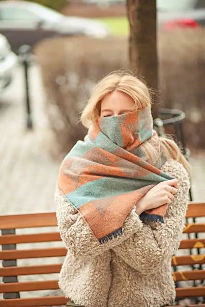 Sıcak eşarplı bir kadın güneşli bir günde klasik mimarinin yanında yürüyor.