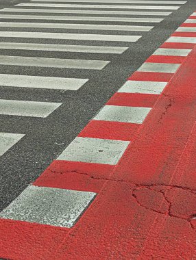 Yaya geçidinde yoğun bir şehir caddesinde güvenliği ve görünürlüğü artıran koyu kırmızı ve beyaz çizgiler yer alıyor..