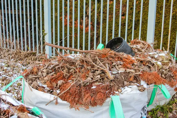 Yaprak ve dallarla dolu bir bahçe atığı, sonbahar sona ererken kenar mahallelerde toplanmaya hazır..