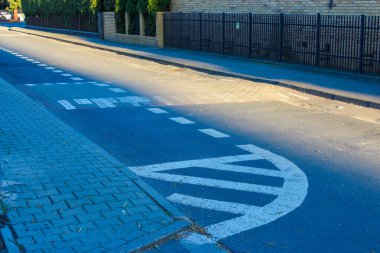 Şehir merkezinde metal çitlerin yanında mavi kaldırım taşına boyanmış beyaz oklarla modern yol işaretleri.
