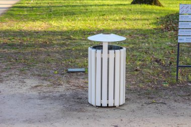 Park yolu üzerindeki modern minimalist beyaz çöp tenekesi temiz tasarım kamu alanı bakımını gösteriyor