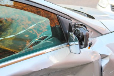 Kazadan veya vandalizmden sonra kablolardan sallanan gümüş arabanın kırık kenar aynası
