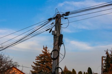 Sunset 'te ağaç silueti ile Mavi Gökyüzüne Karşı Çoklu Güç Hattına sahip Elektrik Aracı Kutbu