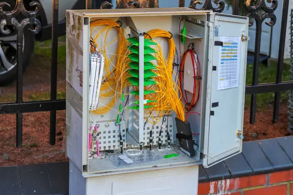 Dışarıdaki duvara renkli kablolar, borular ve devre kesiciler takılı modern elektrik dağıtım kutusu.