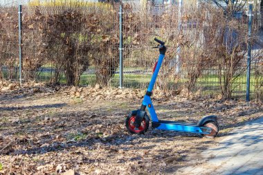 Sonbaharda Şehir Parkı 'nda Çamur Yolu' na park edilmiş Mavi Elektrikli Scooter.