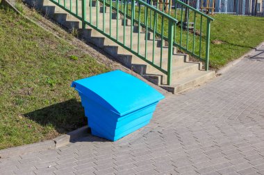 Şehir Park Alanındaki Yeşil Çit 'in yakınındaki Paved Walkway' deki Parlak Mavi Plastik Konteynır