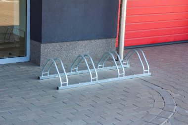 Kırmızı ve Gri Yüzlü Modern Binaya Karşı Beş Otoparklı Metal Bisiklet Rafı