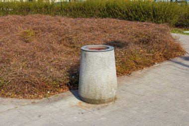Paved Yolu 'ndaki beton atık çöp kutusu Şehir Parkı Ayarlarında kurumuş peyzaj ile