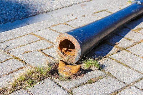Поврежденная голубая металлическая труба с открытым концом и ржавчиной на бетонном покрытии