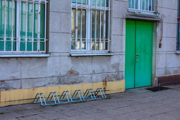 Parlak Yeşil Kapılı Sovyet Dönemi Binası ve Gri Caddedeki Bisiklet Otoparkı