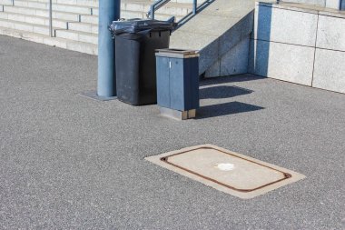Metal Erişim Kapaklı Şehir Kaldırımı ve Beton Duvara Karşı Karanlık Çöp Kutuları
