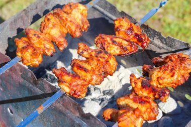 Salamura edilmiş tavuk kebabı ızgarada pişerken gözle görülür kiraz izleri ve sulu bir dokuya sahip.