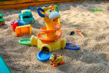 Kum havuzuna dağılmış bina blokları olan renkli plastik çocuk oyuncak ördeği.