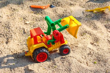 Sarı ve kırmızı plastik oyuncak kazıcı çocukların yaratıcı oyunları için küçük inşaat araçları ile kum havuzunda konumlandırılmış