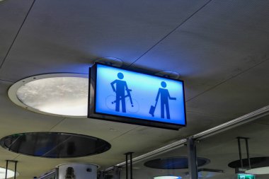 Kamu binasının tavanına erkek ve kadın figürleri asılmış açık mavi tuvalet tabelası.