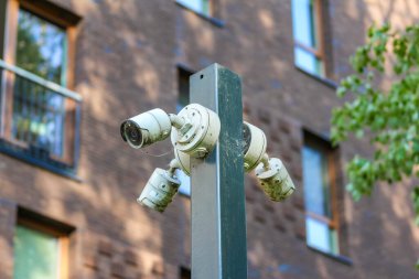Yeşil metal direğe monte edilmiş açık hava güvenlik kamerası kentsel yerleşim alanındaki bina girişini yakalıyor.