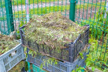 Çevre dostu gübre kutusu bahçe atıkları ve banliyö arka bahçesindeki geri dönüşüm setinde organik materyallerle dolu.