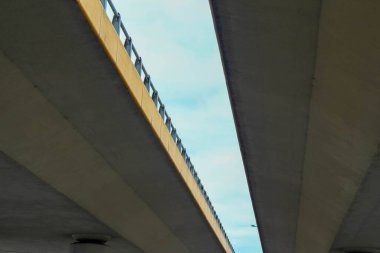 Şehir altyapısını gösteren bulutlu gökyüzüne karşı beton bir otoyol üst geçidinin alt görüntüsü