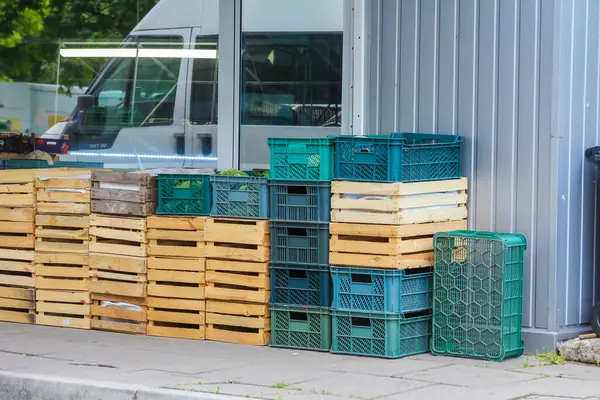 Sanayi deposunun dışındaki ahşap paletlerin yanına istiflenmiş renkli plastik kasalar.