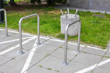 Çağdaş Bisiklet Otoparkı Metal Demiryolları ve Yeşil Çimen üzerinde Beton Çöp Kutusu
