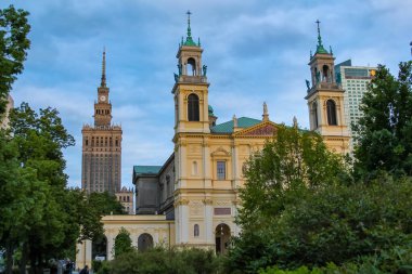 Ağaçlarla çevrili Mavi Gökyüzüne Karşı Altın Kuleleri ve Saat Kulesi olan Tarihi Kilise